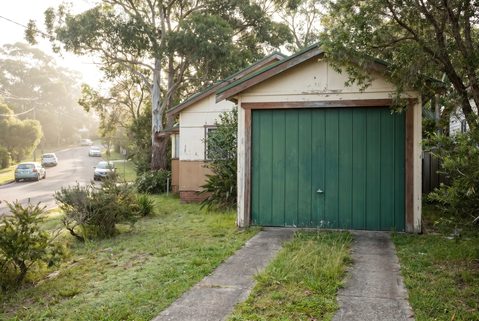 An original 1970s tilt garage door on an older fibro cottage, weathered but standing